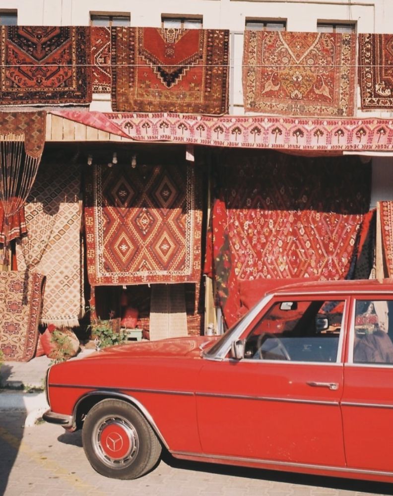 Vintage red Mercedes parked in front of Persian rugs
